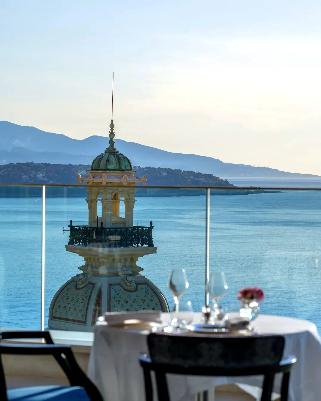 Table dressée face à la mer avec vue sur le dôme d'un palace de la Côte d'Azur